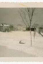 View of campus during winter and person in snow. Written on verso: Middlebury College Campus.