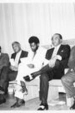 A group men including Dr. Oswald P. Bronson, Robert Threatt, and Dr. J. Deotis Roberts seated on a stage.