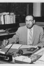 Dr. Harry V. Richardson seated at his desk.
