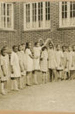 A group of children gather outside in a formation.