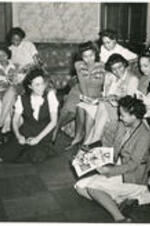 Interior of a dormitory lounge at Atlanta University with a group of seated students reading magazines. Written on verso: Students relax at Atlanta University Dormitory - 1945