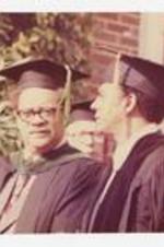 Andrew Young sits next to another man stage at commencement.