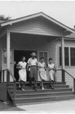 Exterior of a temporary class building with students walking down the front steps. Written on verso: Entrance to new classroom building, July 2, 1947.