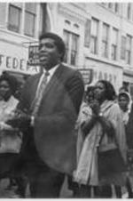 A group of men and women are shown marching, singing, and clapping down the streets of Memphis, Tennessee.
