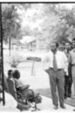 John R. Lewis, Julian Bond, and other men talk with a group of people sitting on a porch in Drew, Mississippi during a voting rights tour.