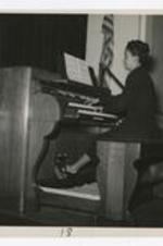 A woman plays the organ piano in the Davage auditorium.
