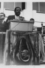 Ralph D. Abernathy is shown speaking at a podium in front of others during a Poor People's Campaign event in Memphis, Tennessee. Senator Ted Kennedy is seated at the far right in the photo.