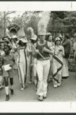 A marking band with children walk down a street.