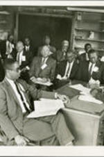 John H. Calhoun, Jr. (seated behind desk) conducting an Adult Citizenship Clinic in Atlanta. Vernon Jordan is one of the attendees.