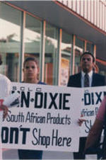 Atlanta Mayor Andrew Young is shown with a youth demonstrator picketing outside of a Winn-Dixie store to protest the store's selling of South African products.