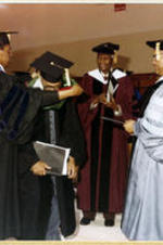 An unidentified man places a green hood around the neck of the 1978 honorary graduate as President Grant Shockley looks on.