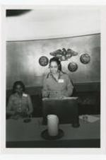 View of a woman at podium and woman in background. Written on verso: "Left to right: Dr. Pearlie Craft Dove; Professor Head Dept of Education; Clark College, 1940's-1986; Dr. Chloe Mitchell, Assoc. Prof. Edu + Psy."