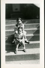 Brailsford R. Brazeal's daughters, Aurelia Erskine and Ernestine Walton Brazeal, sit on the steps of a house.