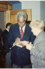 Ossie Davis signs an autograph for a woman.