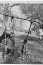 Children of Gammon students play on a slide and swing set.