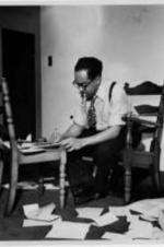 Langston Hughes smokes a cigarette while writing.
