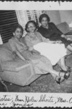 Mrs. Yates &amp; Mrs. Orrie Mae Jones sit together on a sofa in a living room. Written on recto: Mrs. Yates. Mrs. Helen Shorts, Mrs. Orrie Mae Jones.