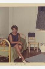 A women sits on a bed in a dorm room.