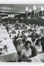 Indoor view of people seated at banquet tables.