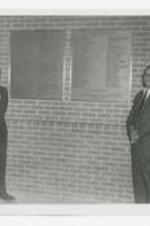 Three men look at two plaques "Centennial Honor Roll on Donors &amp; Workers...In Appreciation by Clark College Alumni Association, December 31, 1969, Atlanta GA." on a brick wall.