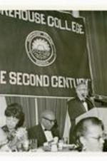 View of a man at a podium. Banner in background reads "Morehouse College, "The Second Century"."