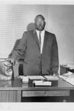 Portrait of Reverend U. L. McKinmon standing behind a desk.