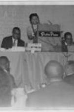 A woman speaks at a Southern Conference of Black Elected Officials meeting. The podium reads "Dinkler Plaza".