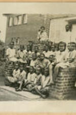 A group of Chadwick School pupils and a teacher sit on the steps of the school.
