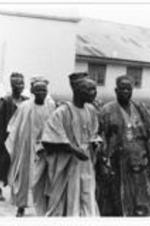 A group of older men walking and talking together. They are wearing traditional African Agbadas.