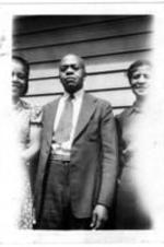 Three unidentified people stand on the side of a house.