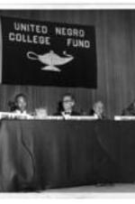 John H. Wheeler sits on stage as part of a United Negro College Fund program. Sitting beside him is Martin Luther King, Jr., August Heckscher, Quincy Howe, and Carl Rowan.