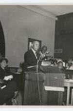 Indoor view of a man speaking at a podium. Written on verso: speaker to the members of the West Texas Annual Conference at St. Andrews Church, Fort Worth Texas, May 5, 1962.