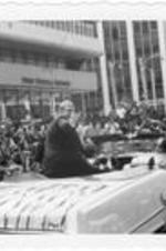 Parade Grand Marshall, actor Raymond Burr, waves to crowd from a car. Written on accompanying document: Raymond Burr Grand Marshall.