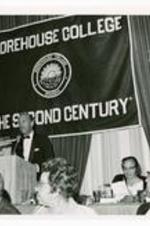 View of man standing behind podium, banner in background "Morehouse College, 'The Second Century'."