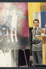 Maynard Jackson stands in front of a painting and claps.