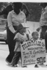 Two toddlers carry a sign that reads "Pilgrimage to Washington - Turn To Each Other, Not On Each Other" while guided by an adult standing behind them.