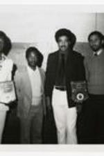 Group portrait of four men. Written on verso, "Left to right: (Morris Brown College), Ezra Johnson - Football Player, Cass Johnson - Football Coach, Charles Hardnett - Athletic Director, Bill Wade- Basketball Player".
