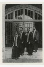 A portrait of four men wearing graduation gowns.