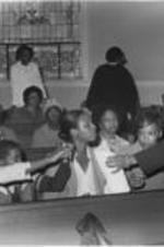 An unidentified woman is shown handing a cloth to a woman at the National Women's Candlelight Prayer Service held during the three day Martin Luther King, Jr. memorial observance in April 1981. The prayer service was dedicated to the memory of Atlanta's missing and murdered children and their families.