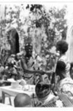 An unidentified man wearing an Agbada shakes a woman's hand at the alter as others look on.