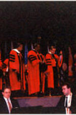 Men in regalia stand on a stage for C. Eric Lincoln receiving an honorary degree from Boston University.