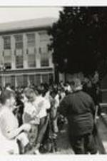 Two men perform for a crowd on the steps of a building at a homecoming concert.