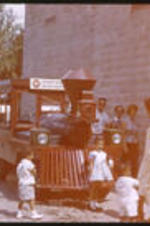 Anna Henderson and her children standing in front of a tourist train at an amusement park.