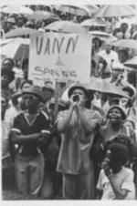 A crowd of protesters are seen standing with umbrellas and a protest sign that reads "Vann &amp; Sands Must Go" at a demonstration to protest the killing of Bonita Carter by a Birmingham police officer.