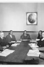 Dr. Harry V. Richardson (center) sits in a meeting with faculty. Written on verso: Roger Guptill, Furhman, Dr. Richardson, Dr. Copher, Granhamm, Dr. Clelland.