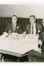 View of three men and a woman seated in a dining booth.