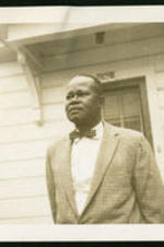 Trezzvant Anderson stands in front of a house in a suit.