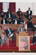 Johnnie Carr is shown speaking at a memorial service for Rosa Parks at Ebenezer Baptist Church while Joseph E. Lowery, Reverend James Orange, Reverend Fred Taylor, and others listen.