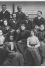 An unidentified group of young men and women seated on the steps of a house.