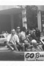 Phil Niekro, Mike Lum, and others ride on a car in a Braves pennant Rally parade.